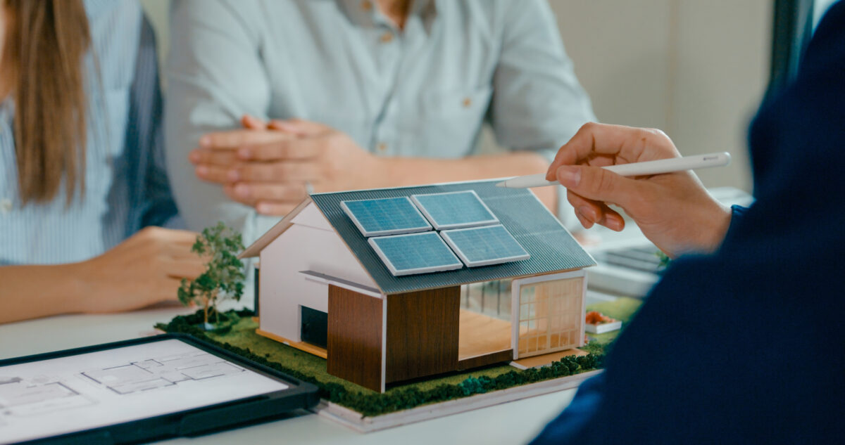 Closeup of young couple in detailed consultation with real estate agent, who is highlighting advantages of home with solar panels. Consulting on Eco-Friendly Home with Real Estate Agent Concept.